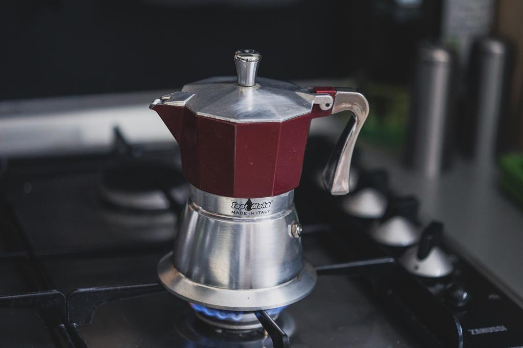 Гейзерная кофеварка на газовой плите в процессе заваривания кофе